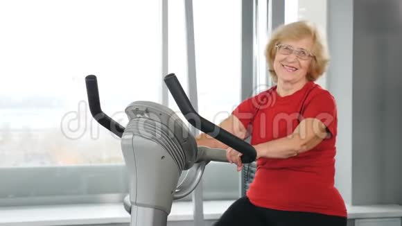 健身中心活跃的老年女性骑自行车做有氧训练的肖像健康活跃的老年妇女视频的预览图