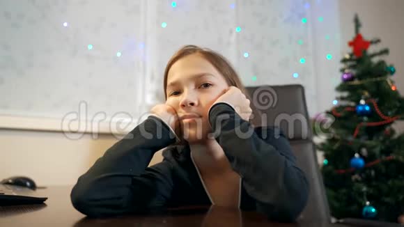 悲伤的女孩坐在圣诞树附近的一张桌子旁双手抱着头视频的预览图