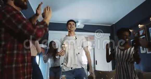 快乐的千禧年欧洲男学生与朋友在多民族生日派对慢动作中跳舞视频的预览图