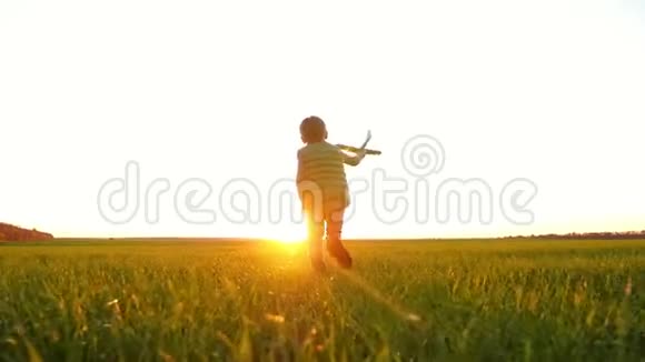 一个孩子穿过田野里的绿草向太阳跑去一个小男孩玩玩具飞机把它扔出去视频的预览图