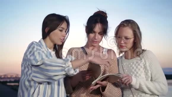 三个女朋友在外面看杂志视频的预览图