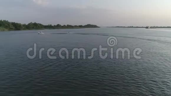 运动员在摩托艇后的尾板上冲浪的航拍镜头水沿着河流缓慢地流动视频的预览图