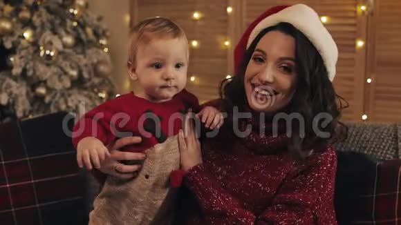 圣诞节快乐的年轻母亲和儿子看着你坐在客厅沙发上的镜头视频的预览图
