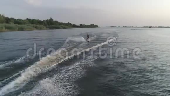 Drone射击运动男子骑在摩托艇后面在大自然的暑假里沿着河边溅起水花视频的预览图