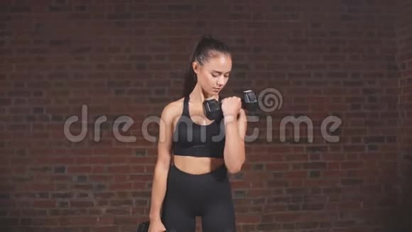 穿着黑色运动服在健身房里装哑铃的年轻女性视频的预览图