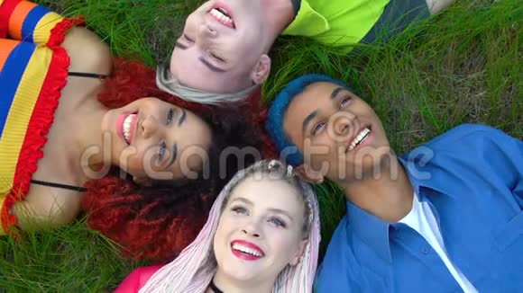 快乐的多种族女性和男性潮人躺在草地上欢笑朋友视频的预览图
