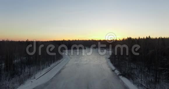 日出时鸟瞰冬季森林和冰冻河流视频的预览图