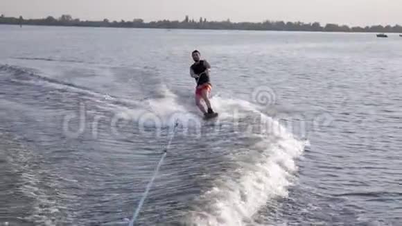 冲浪酷酷的运动员乘坐摩托艇后的船在河上与溅水背景自然视频的预览图