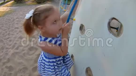 孩子在爬墙上爬在操场上玩儿童体育游戏的小女孩视频的预览图