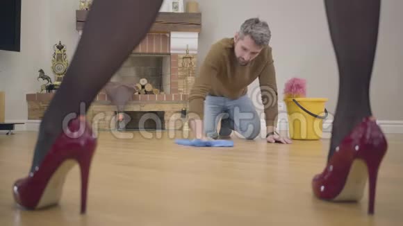 一个白人成年人在地板上洗衣服他的妻子或女朋友说话的肖像漂亮的女腿视频的预览图