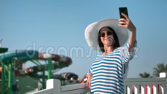 在豪华度假胜地水上乐园的背景下放松的年轻游客微笑着自拍视频的预览图