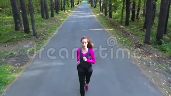 女人在一条笔直的路上穿过森林年轻女子穿过森林视频的预览图