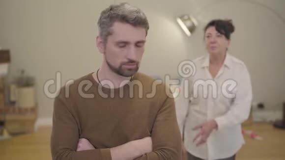 愤怒的白种人白发男子听着他的母亲责怪他的背景家庭关系问题视频的预览图