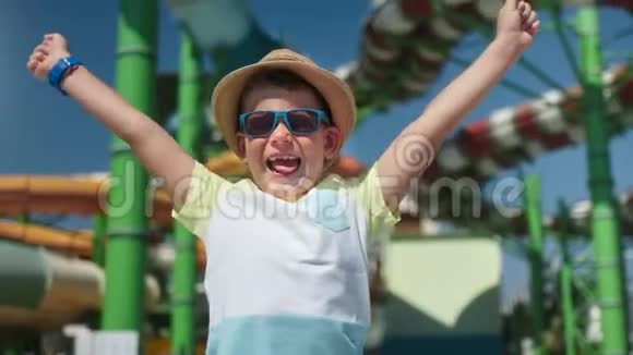 在露天水上乐园快乐的时髦男孩笑着玩着举起手来感受积极的情绪视频的预览图
