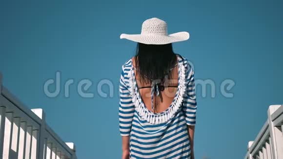 在蓝天背景下背着白色帽子举手欣赏暑假视频的预览图