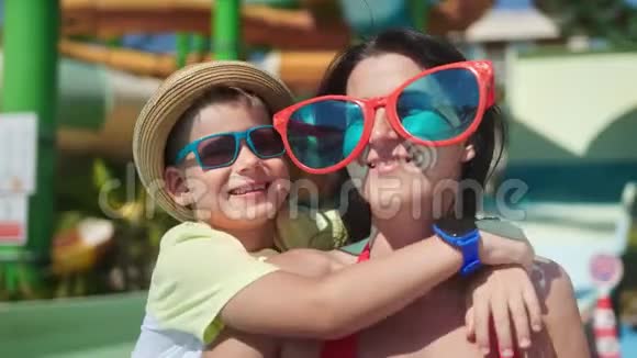 笑的女人戴着大大的滑稽眼镜拥抱着小儿子一起享受假期玩得开心视频的预览图