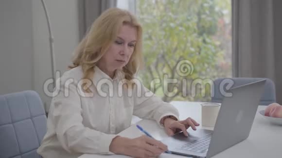 严肃成熟的白种人女性坐在家里在网上工作自信的商务小姐穿着白色衬衫视频的预览图