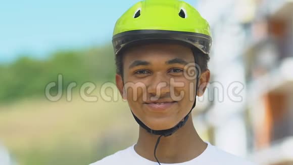 戴着自行车头盔的青少年男孩微笑着进入摄像头冒险骑自行车道路安全视频的预览图