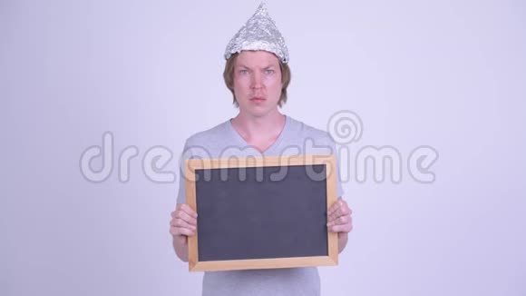 戴着锡纸帽的年轻人拿着黑板看上去很害怕视频的预览图