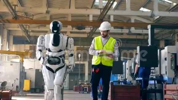 机器人在一位男性专家的控制下沿着工厂行走视频的预览图