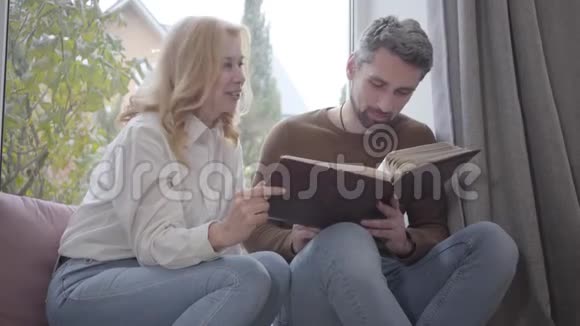 成熟的白种女人和成年白发男人合影母子俩在家里分享回忆幸福的家庭视频的预览图