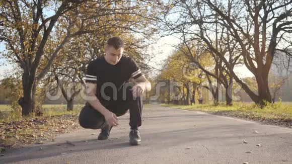 成年白种人穿着黑色运动鞋系鞋带然后离开小男孩花时间在秋天的公园里视频的预览图