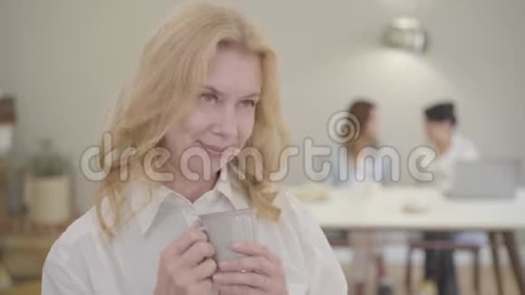 美丽成熟的白种人女人的肖像金发和灰色的眼睛穿着白衬衫的高级夫人视频的预览图