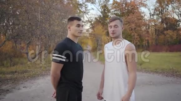 两位积极的白人健美运动员在秋天公园与镜头交谈并开始疯狂跳舞的肖像视频的预览图