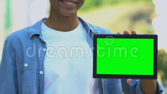 用绿色屏幕在平板电脑上指指点点的美国黑人少年微笑视频的预览图