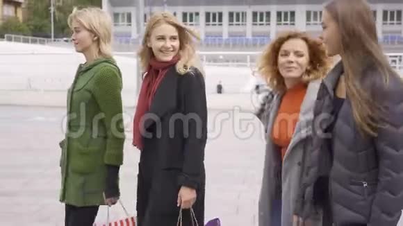 四个漂亮的女朋友在街上快乐地交谈四个带着购物袋的时尚女性视频的预览图