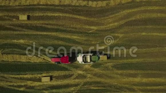农业机器在阳光明媚的夏日在田间工作拖拉机正把干草压成方捆视频的预览图