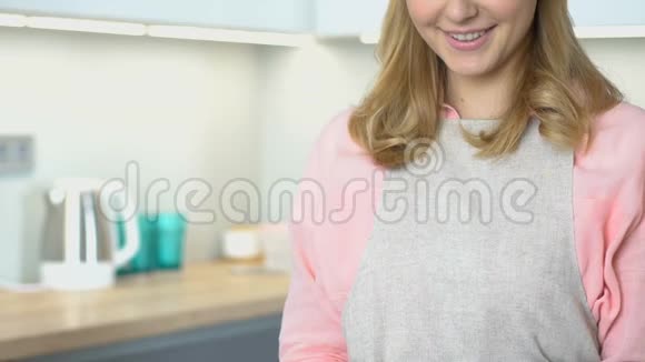 穿着围裙的女人站在厨房对着镜头微笑家庭主妇画像视频的预览图