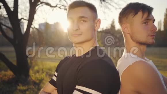 两个年轻的高加索健美运动员站在阳光下看着镜头的特写镜头英俊强壮的运动员视频的预览图