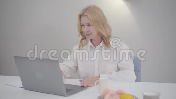 成熟的白人女性坐在笔记本电脑和视频电话自信的商务小姐穿着白色衬衫在网上聊天视频的预览图