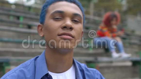 自信的蓝发黑人少年在镜头前微笑青春期视频的预览图