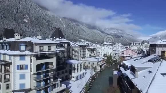 神奇的空中无人机飞行在晴朗的蓝天上的豪华别墅村在雪冬森林阿尔卑斯山视频的预览图