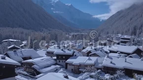 美丽的小别墅舒适的房子别墅雪覆盖村庄阿尔卑斯山山脉空中景观冬季的一天视频的预览图