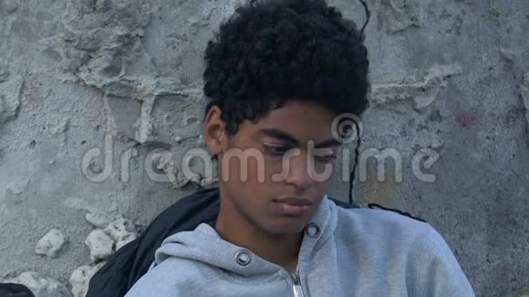 黑人男性青少年嘴唇擦伤坐在街道上睡袋烦恼视频的预览图