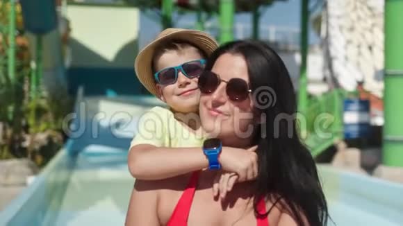 小可爱的男孩拥抱年轻的母亲一起摆姿势在豪华度假村水上乐园的背景视频的预览图