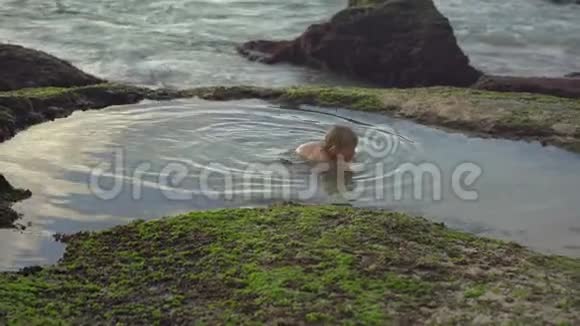 在巴厘岛的潘泰泰特加尔旺吉海滩小男孩在一个带有海水的天然小池塘里玩得很开心视频的预览图