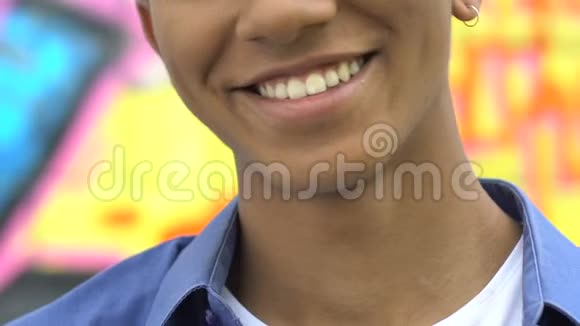 快乐的美国黑人蓝发年轻男性戴着耳环在镜头前微笑视频的预览图