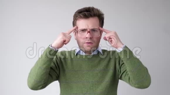 戴大眼镜的人把手指放在太阳穴上试图记住或产生想法视频的预览图
