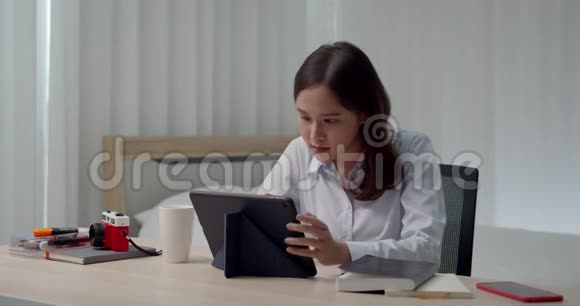 一位在家拿平板电脑工作的亚洲年轻女性视频的预览图