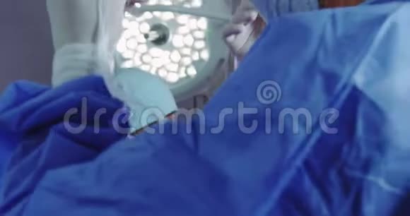 协助男医生在手术室佩戴外科口罩的女医生特写视频的预览图