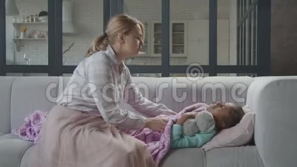 爱抚的妈妈在沙发上安慰困倦的生病的孩子视频的预览图