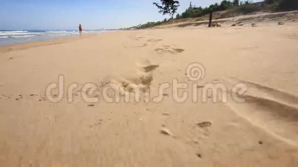 摄影机沿湿沙留下的脚印移动视频的预览图