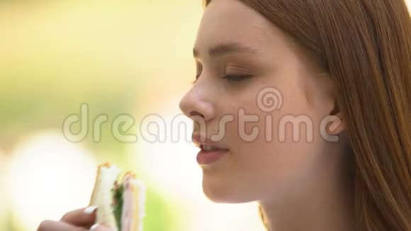 红发少女咬嚼三明治不健康饮食街头小吃视频的预览图