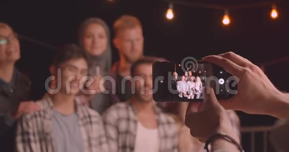 在舒适的欢乐聚会上在Instagram相机上拍摄各种不同种族的朋友的特写照片视频的预览图