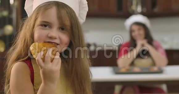 一个漂亮的白人女孩在家里的厨房里吃面包可爱的孩子享受美味的面包店因为她的母亲坐着视频的预览图
