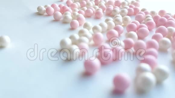 小珍珠母白色和粉红色球或化妆粉珠滚动在白色背景最小的想法概念4k视频的预览图